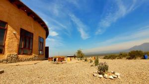 a building in the middle of a field next to a mountain at KONDUR ELEMENTOS ECO HOSTEL in Las Compuertas