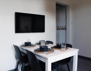 een witte tafel met zwarte stoelen en een televisie aan de muur bij Victoria Cottage in Cannock