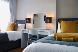 a bedroom with two beds and a desk and a mirror at Victoria Cottage in Cannock