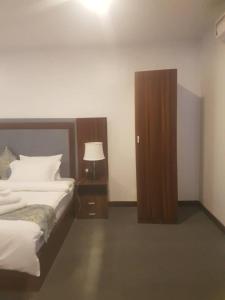a bedroom with a bed and a night stand with a lamp at Blue-View Suites & Apartments in Abuja