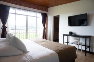 Un dormitorio con una cama y una ventana grande. en Hotel San Marcos, en Paipa