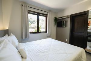 a bedroom with a large white bed with a window at Malbec Casa Hotel in Bento Gonçalves