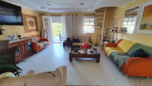 a living room with couches and a tv at Suítes Maravilha Arraial do Cabo in Arraial do Cabo