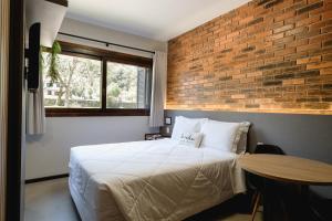 a bedroom with a bed and a brick wall at Malbec Casa Hotel in Bento Gonçalves