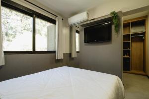 a bedroom with a white bed and a tv at Malbec Casa Hotel in Bento Gonçalves