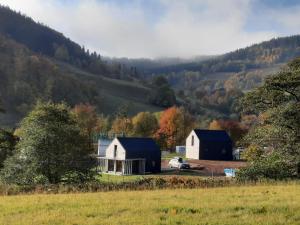 una granja con dos graneros y un coche en un campo en Domek Nasze Miejsce, en Łomnica