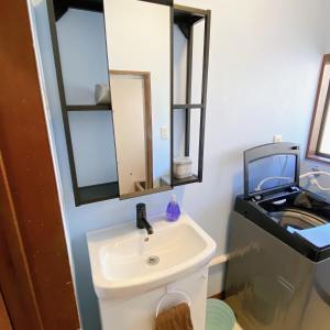 ein Bad mit einem Waschbecken und einem Spiegel in der Unterkunft mooi 宮町 in Aizu-Wakamatsu
