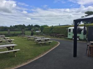 a bunch of picnic tables in a field with a truck at Stoneyford Luxurious Cabins in Stonyford