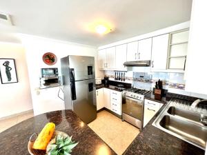 a kitchen with white cabinets and a black counter top at Encantador departamento frente al mar con WIFI in Tonsupa