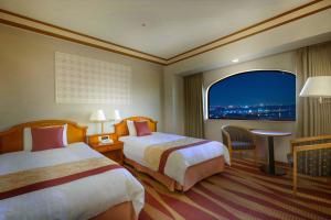 a hotel room with two beds and a window at Hotel Plaza Kobe in Kobe