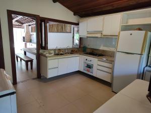 eine Küche mit weißen Schränken und einem weißen Kühlschrank in der Unterkunft Linda casa 4/4 com piscina na Praia do Forte. in Mata de Sao Joao