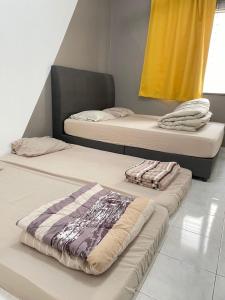 two twin beds in a room with towels on them at 8min Port Dickson beach 17pax Pet Friendly in Port Dickson