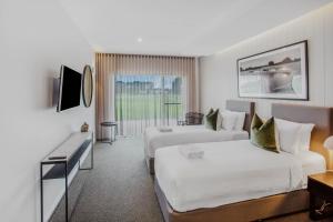 a hotel room with two beds and a television at 13th Beach Golf Lodges in Barwon Heads