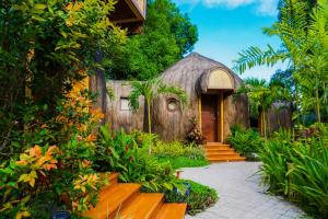 una casa con techo de paja y una pasarela en UNWND Boutique Hotel Dumaguete, en Dumaguete