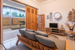 a living room with a couch and a tv at Villa D'Bamboo by Plesirhati Yogja in Yogyakarta