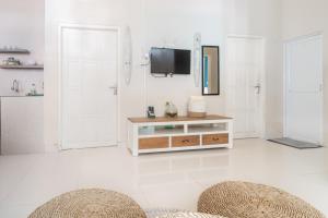 a white living room with a television and two stools at D'Minggiran by Plesirhatiyogya in Timuran