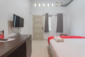 a bedroom with a bed and a desk with a television at RedDoorz Plus Syariah @ Tuparev Cirebon 3 in Cirebon