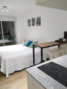 1 dormitorio con cama blanca y mesa en Aires Verdes Apart Deluxe en Salta
