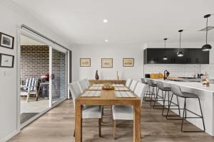 a kitchen and dining room with a wooden table and chairs at Libbity's at The Point by Experience Jervis Bay in Sanctuary Point