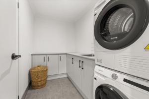 a white laundry room with a washer and dryer at Libbity's at The Point by Experience Jervis Bay in Sanctuary Point