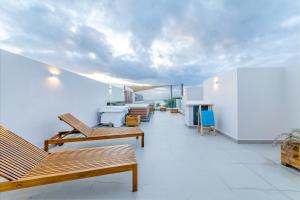 a balcony with wooden benches on a white wall at One Bay Residence Unit 15 - Penthouse with private roof top, jacuzzi and sea view in Grand-Baie