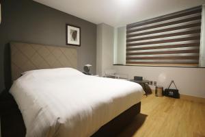 Un dormitorio con una gran cama blanca y una ventana en Gumi Century Hotel, en Gumi