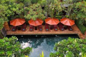 a group of orange umbrellas sitting next to a pool at The Moon Residence & Spa in Siem Reap