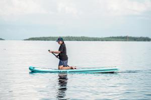 Un homme est assis sur une planche de paddle sur l'eau dans l'établissement Sinuan Homestay, 