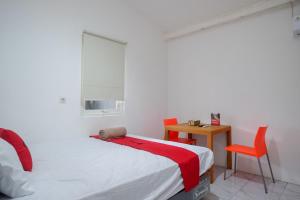 a bedroom with a bed and a table and a chair at RedDoorz Hostel near Lawang Sewu Semarang in Kalibanteng-lor