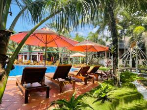 a group of chairs and umbrellas next to a pool at Orange Resort in Phu Quoc