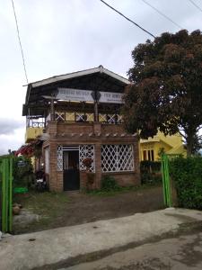 a brick building with a tree in front of it at Berastagi Mountain View Homestay & Pizzeria in Berastagi