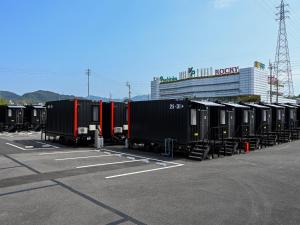 eine Reihe von Zugautos auf einem Parkplatz in der Unterkunft HOTEL R9 The Yard Shikokuchuo in Shikokuchuo