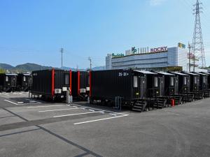 a row of train cars parked in a parking lot at HOTEL R9 The Yard Shikokuchuo in Shikokuchuo