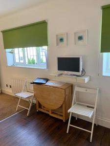 Habitación con escritorio, ordenador y 2 sillas. en Between Piers, the stylish studio flat in Cannon place, en Brighton & Hove