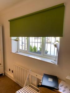 una ventana con una persiana verde en una habitación en Between Piers, the stylish studio flat in Cannon place, en Brighton & Hove