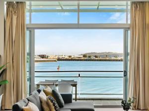 a living room with a large window looking out at the water at Relaxing Sea Wharf View Apartment in Auckland