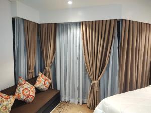 a bedroom with curtains and a bed and a couch at Tambuli Residence in Maribago