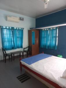 a bedroom with a bed and a table and chairs at Sun n Tan Beach Home stay in Kannur