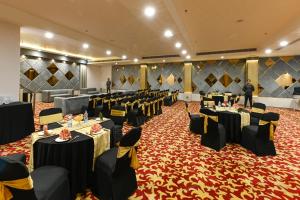 um salão de banquetes com mesas e cadeiras numa sala em Hotel Avalon Palms Agra em Agra