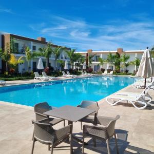 uma piscina com cadeiras e uma mesa em frente a um hotel em Hermosa townhouse boca paraíso em Boca Chica
