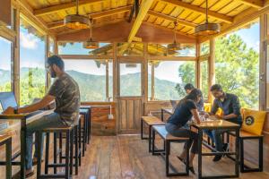 a group of people sitting at tables in a restaurant at The Hosteller Ramgarh, Nainital in Rāmgarh