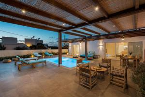 an outdoor patio with a pool and tables and chairs at Citrus Seaside Houses in Plaka