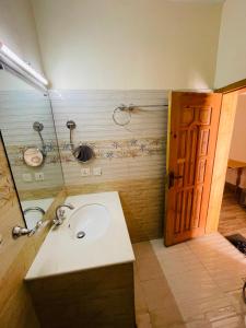 a bathroom with a sink and a mirror and a door at Karakorum View Hotel Karimabad Hunza in Hunza