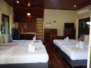 una camera con tre letti con lenzuola bianche di BaanSuanLeelawadee Resort Amphawa a Amphawa