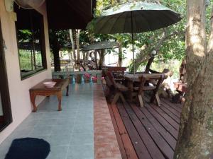 a wooden deck with a table and an umbrella at BaanSuanLeelawadee Resort Amphawa in Amphawa