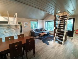 a living room with a couch and a table and stairs at Hietavilla Pläk- Hot tube - Sauna - AC - Fireplace - 11kW EV-refuel - Landscape view - Silence - Free WiFi in Ruka