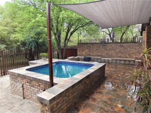 a swimming pool with an umbrella in a backyard at Weltevrede Lodge - Self Catering Houses in Marloth Park