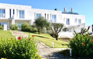 un edificio blanco con flores delante en Resort con piscina a soli 250 mt dalla spiaggia La Pelosa, en Stintino