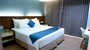 um quarto com uma grande cama branca com lençóis azuis em Hotel Ayola Sunrise Mojokerto em Mojokerto