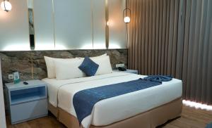 a bedroom with a large bed with blue and white pillows at Hotel Ayola Sunrise Mojokerto in Mojokerto